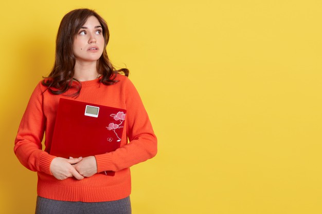 diet-weight-young-frustrated-woman-looking-aside-with-pensive-facial-expression-feeling-unhealthy-embracing-mechanical-scales-wearing-orange-sweater-poses-yellow_176532-13469.jpg